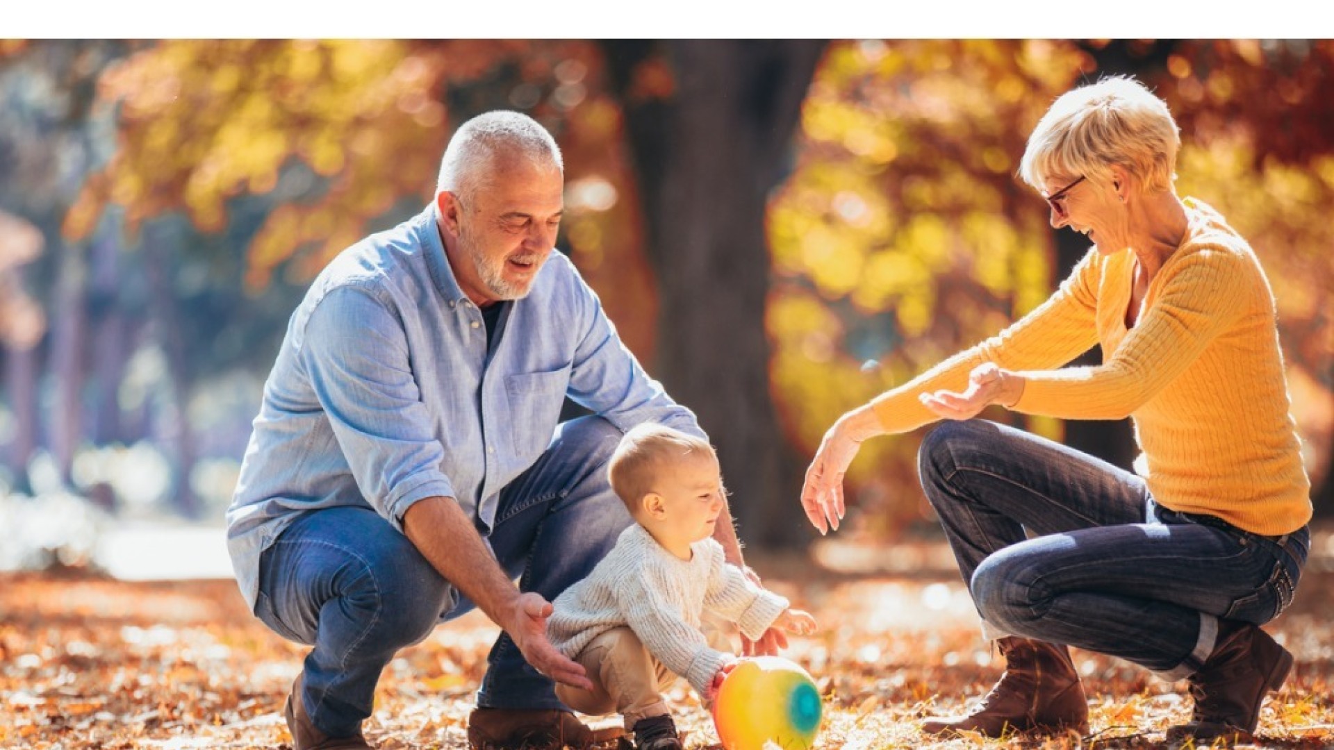 Opa en oma spelen met hun kleinkind in een park in de herfst.