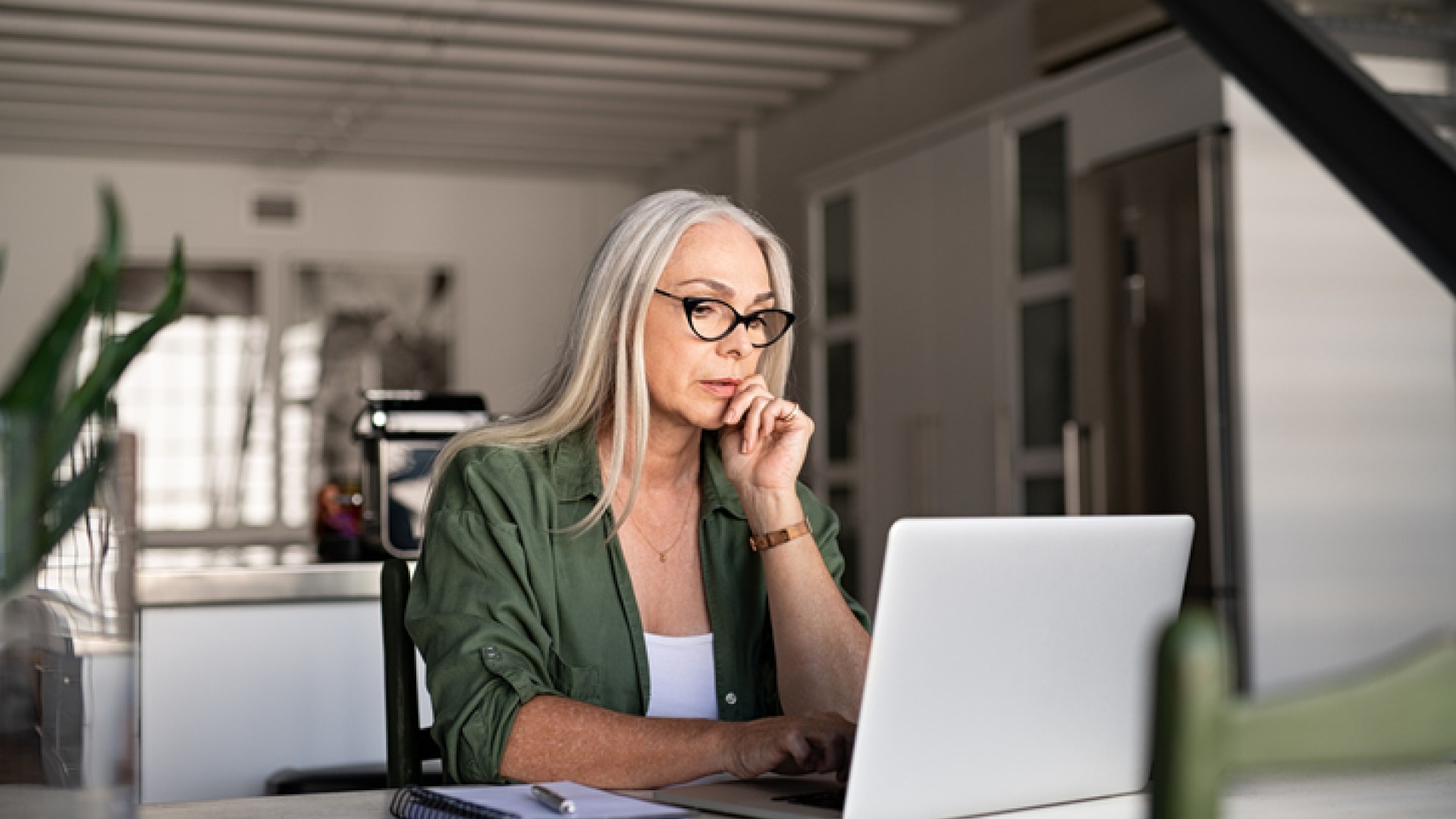 Vrouw werkt geconcentreerd op een laptop aan een tafel.